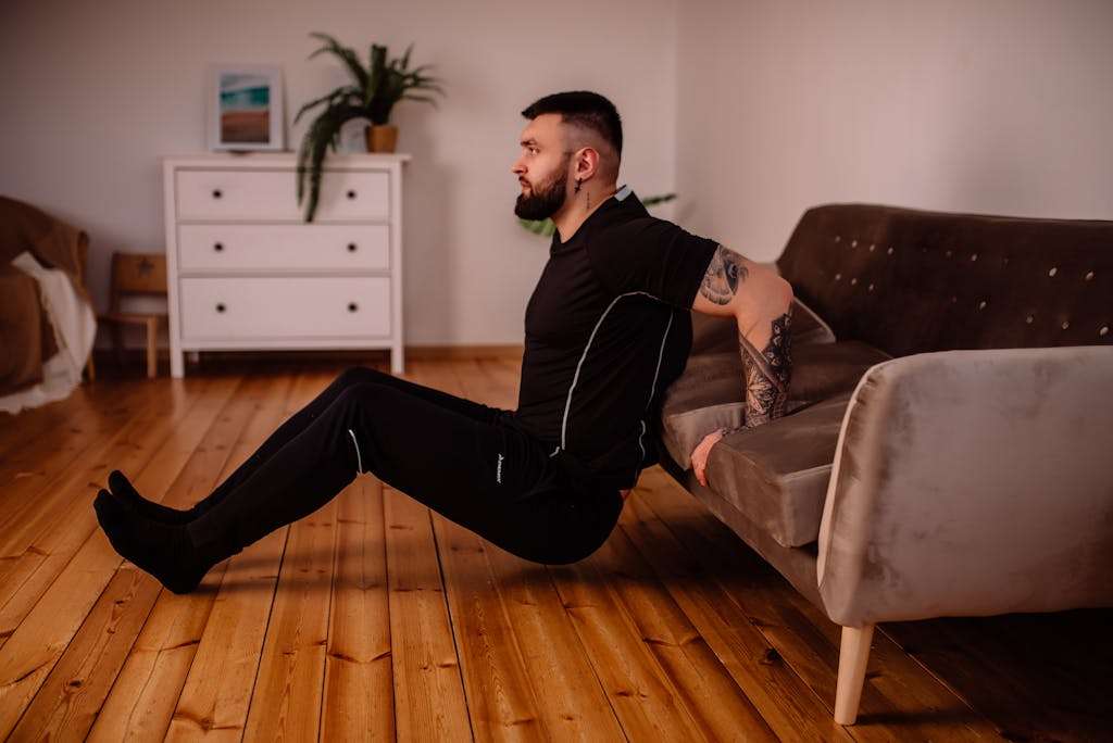 Man in Black Crew Neck T-shirt and Black Pants Sitting on Brown Couch