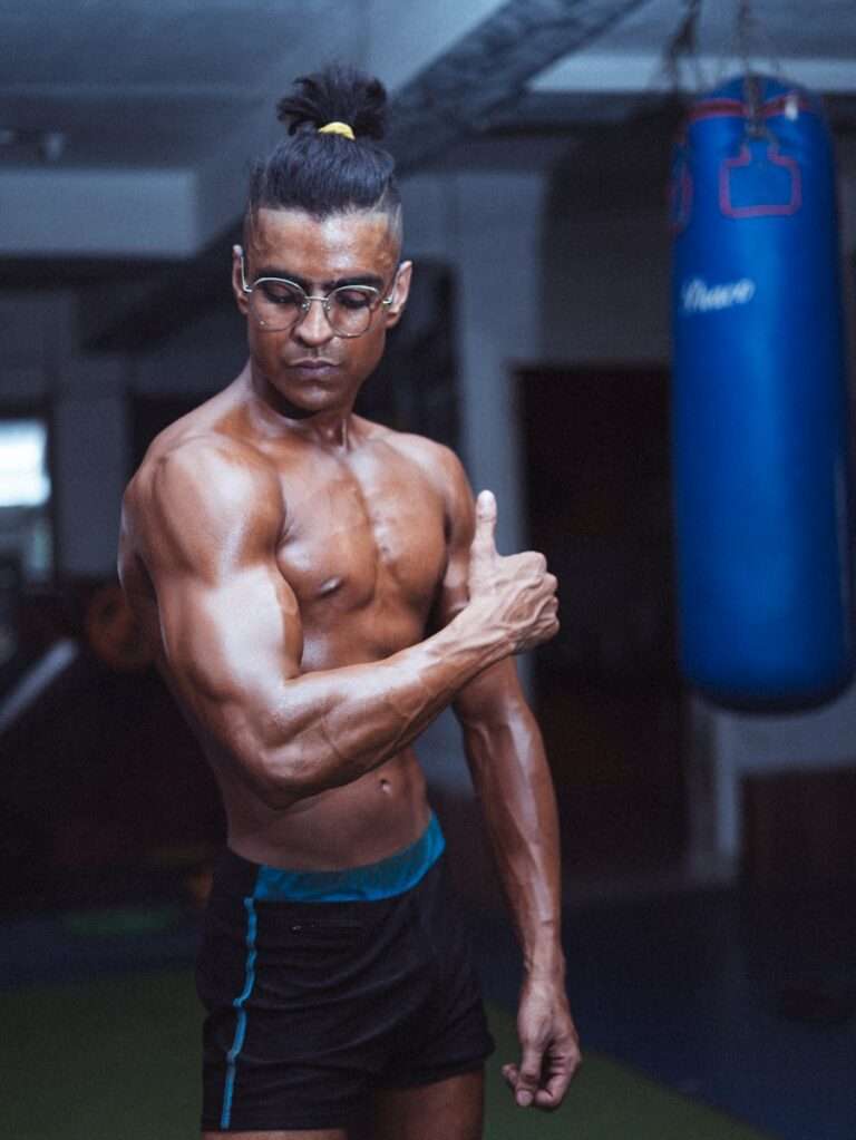 topless man in red shorts holding blue exercise ball