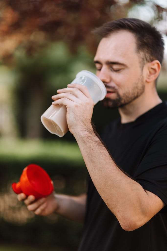 Man in Black Crew Neck T-shirt Drinking from a Plastic Tumbler