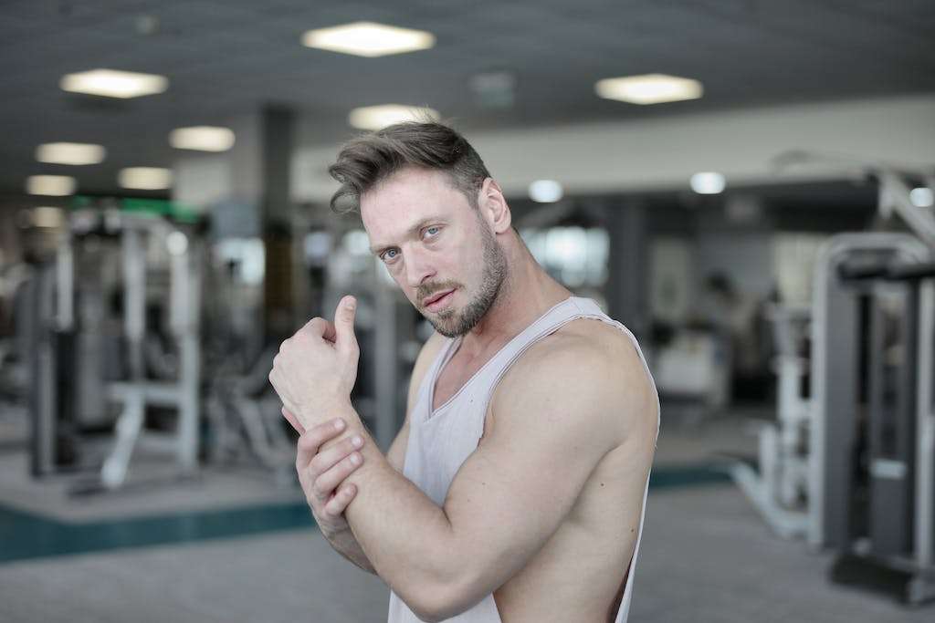 Serious male athlete standing in gym and looking at camera