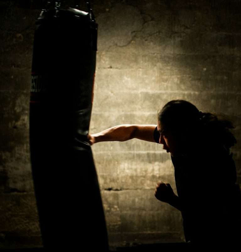 a woman is punching a punching bag in a dark room